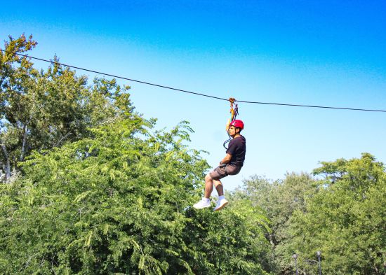 alt-text a man on a zip line surrounded by greenery - Adventure Park near Ahmedabad
